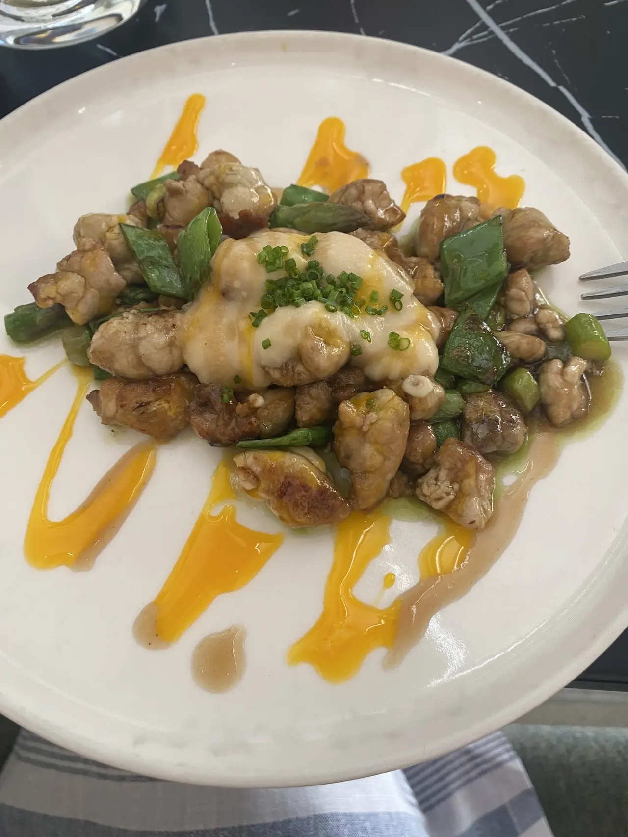 Sauteed diced meat with green beans and creamy sauce on a white plate