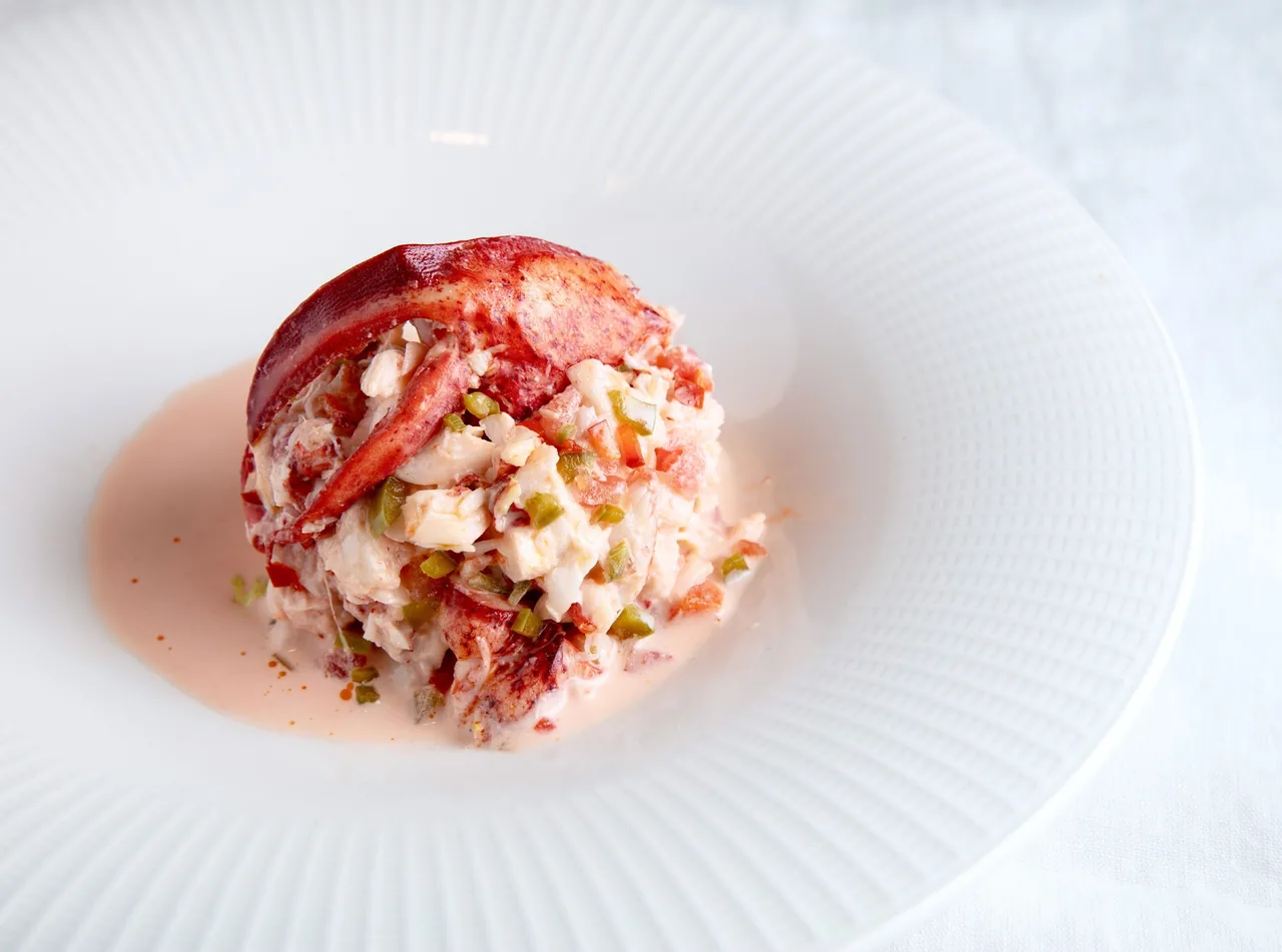 A round mound of shredded seafood in a pale sauce on a white plate
