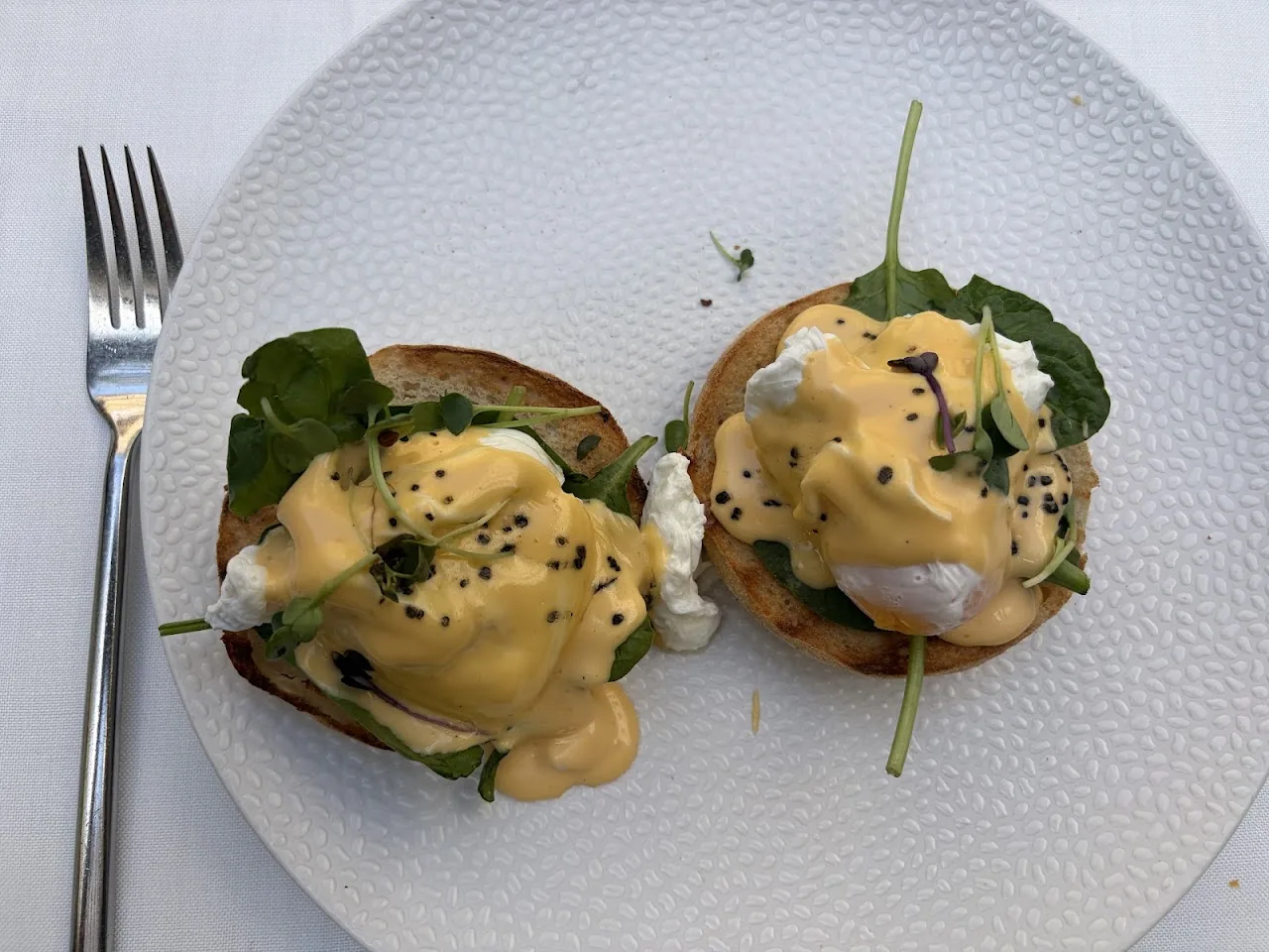Two eggs benedict topped with sesame seeds on toasted buns