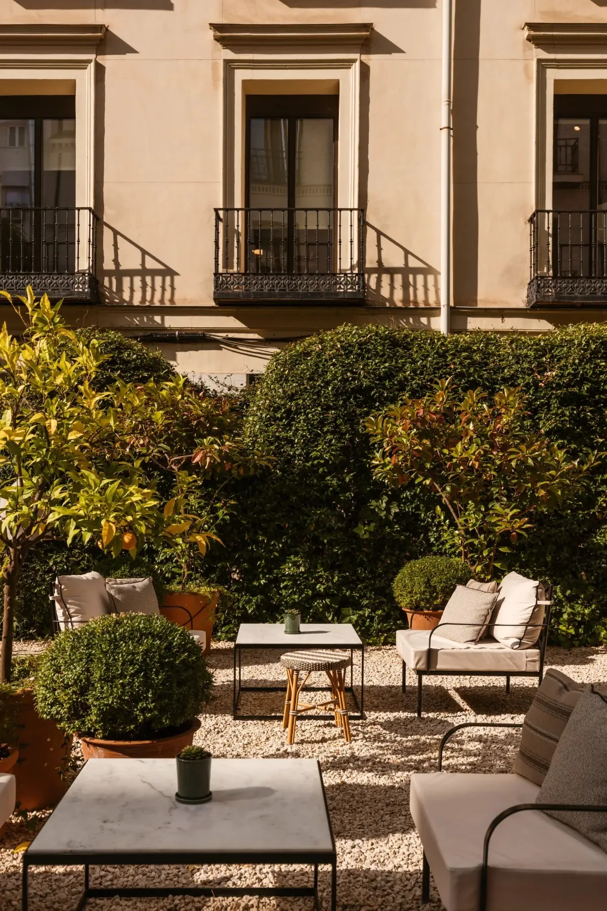Garden terrace with low tables and cushioned seating in front of a building facade
