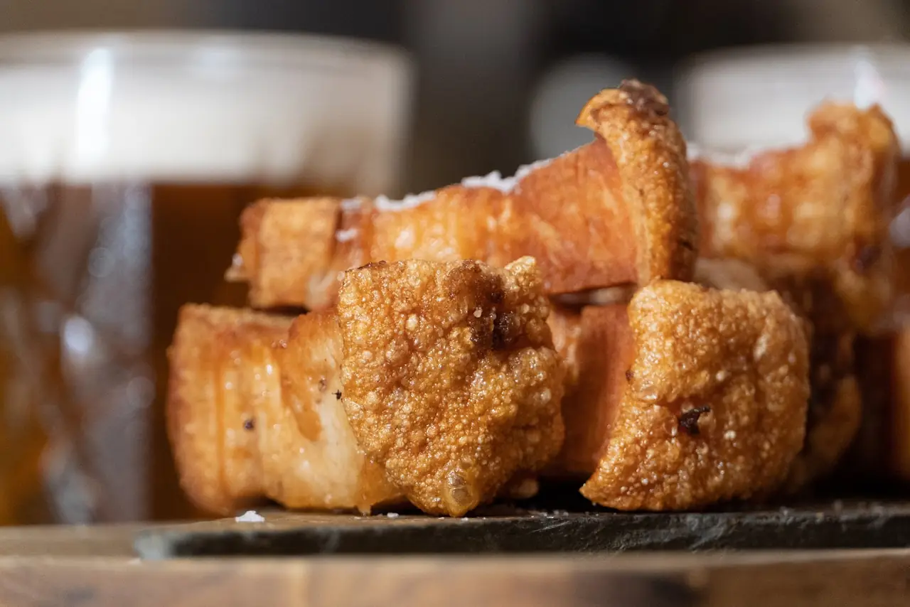 Close-up of crispy fried pork belly chunks with crackling skin on a slate board