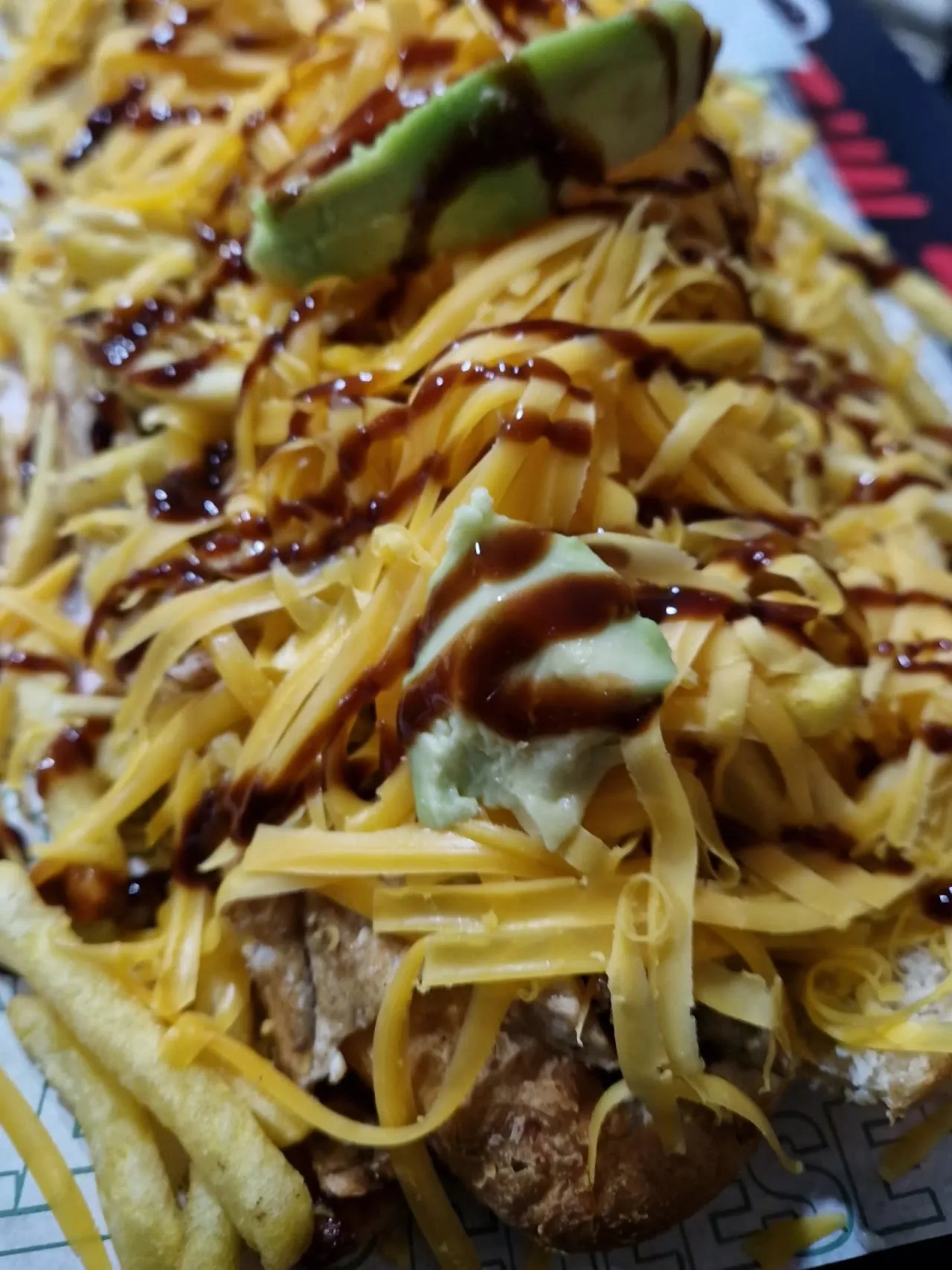 Fries topped with sauce, avocado, and shredded cheese
