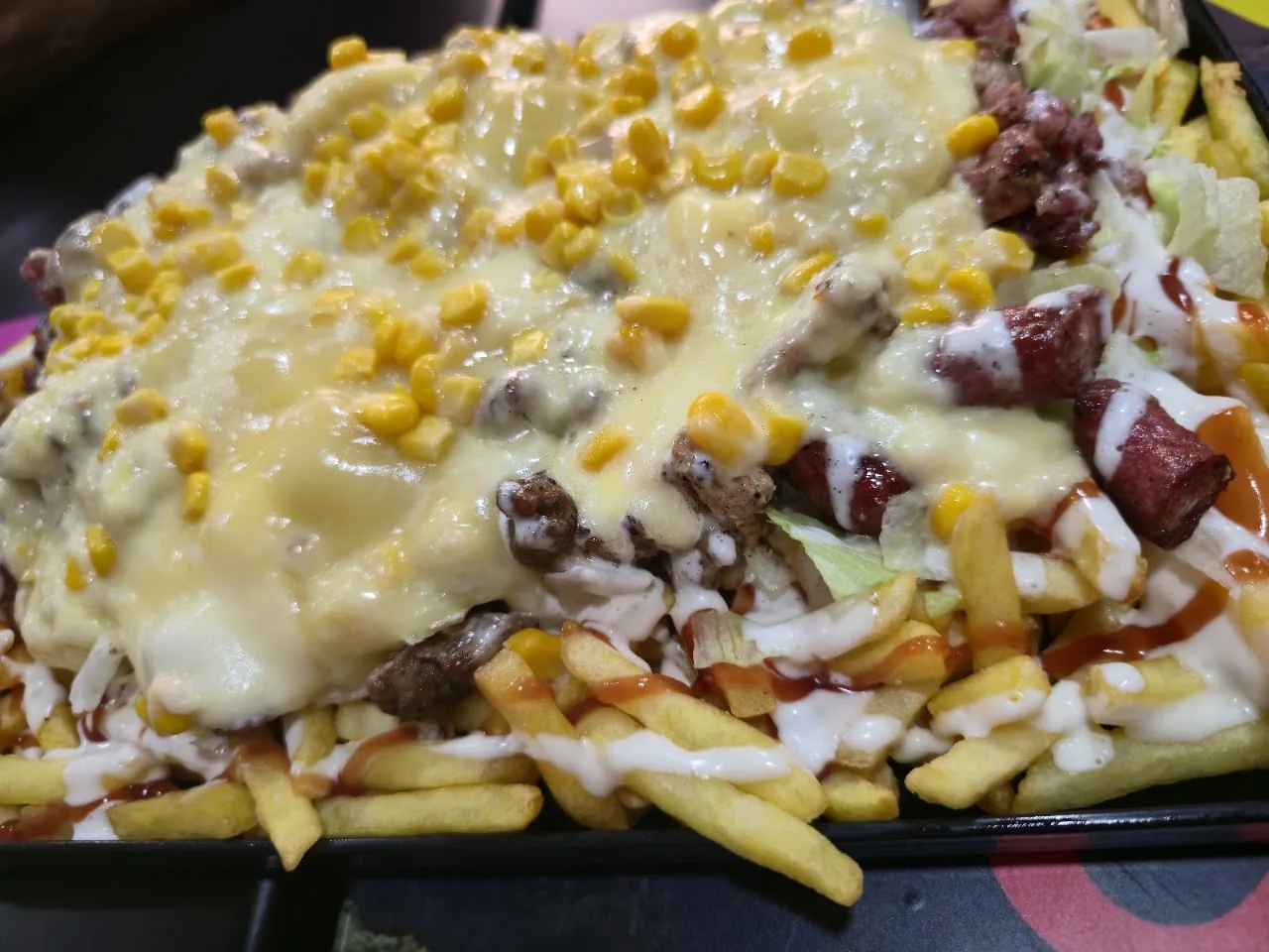 Fries topped with corn, meat, and melted cheese