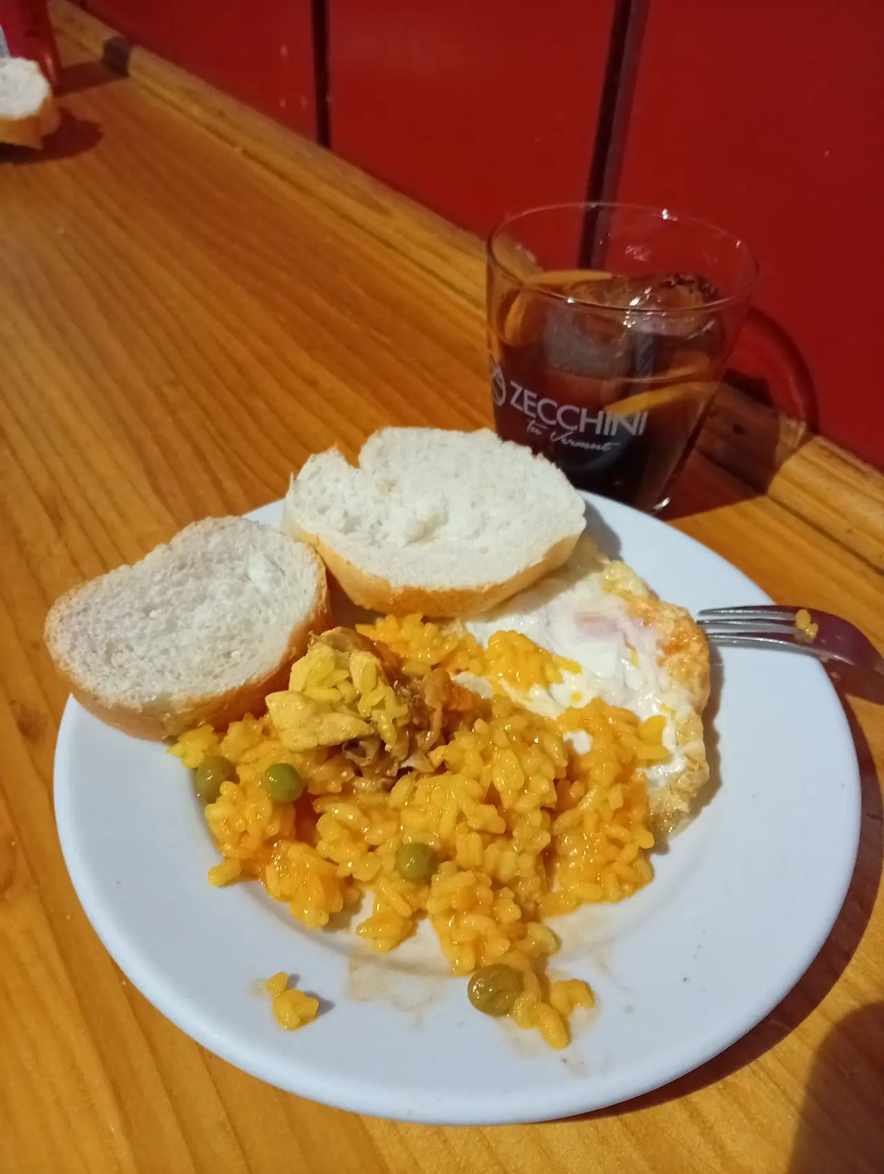 Yellow rice with peas and a fried egg, with bread, on a wooden bar