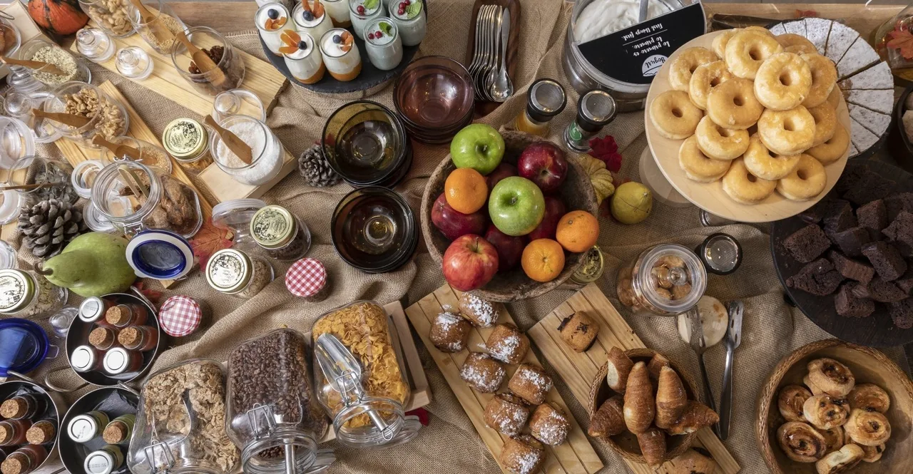 A large spread of pastries, fruit, bread and small dishes seen from above