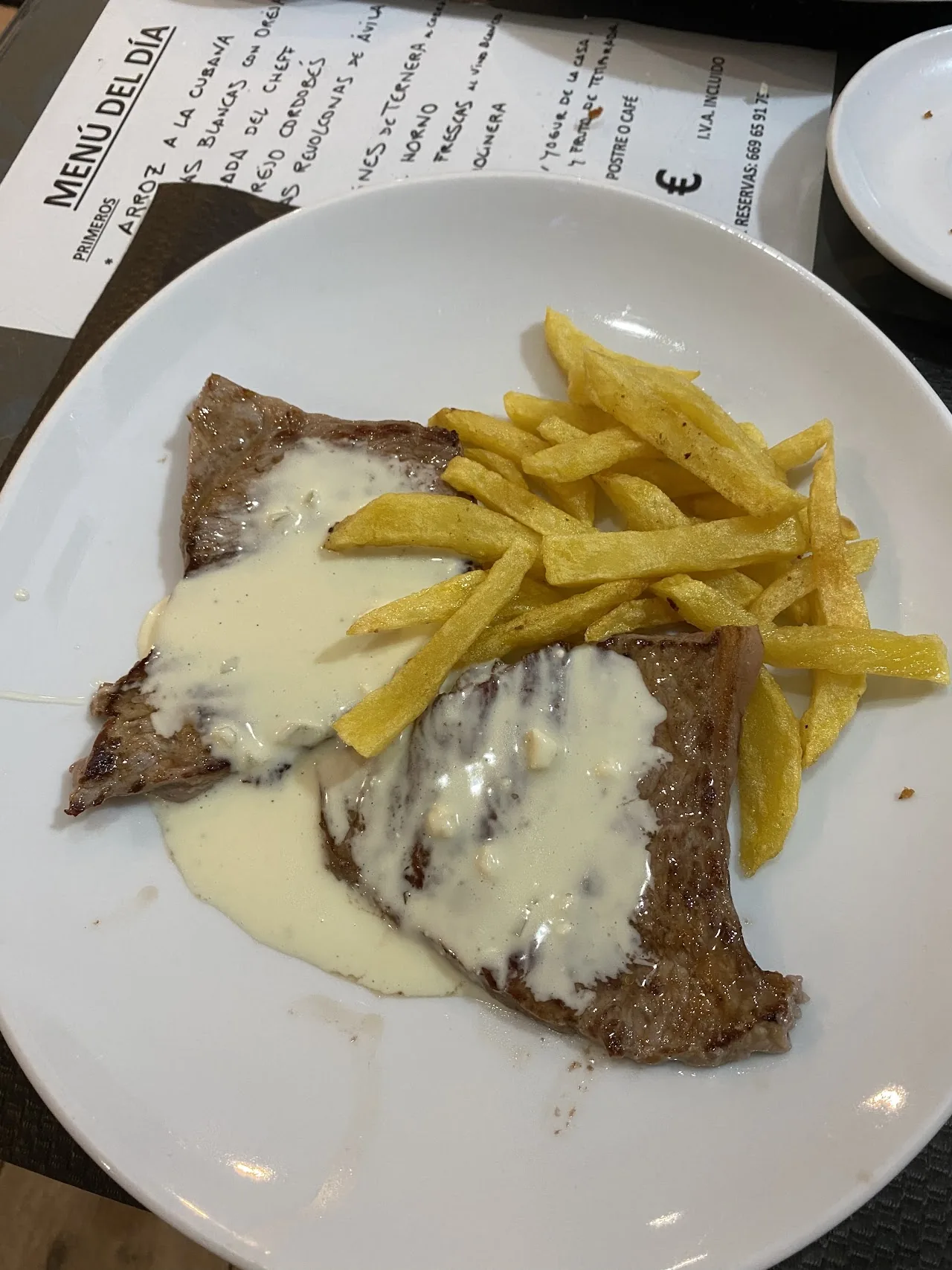 A breaded cutlet with fries in white sauce
