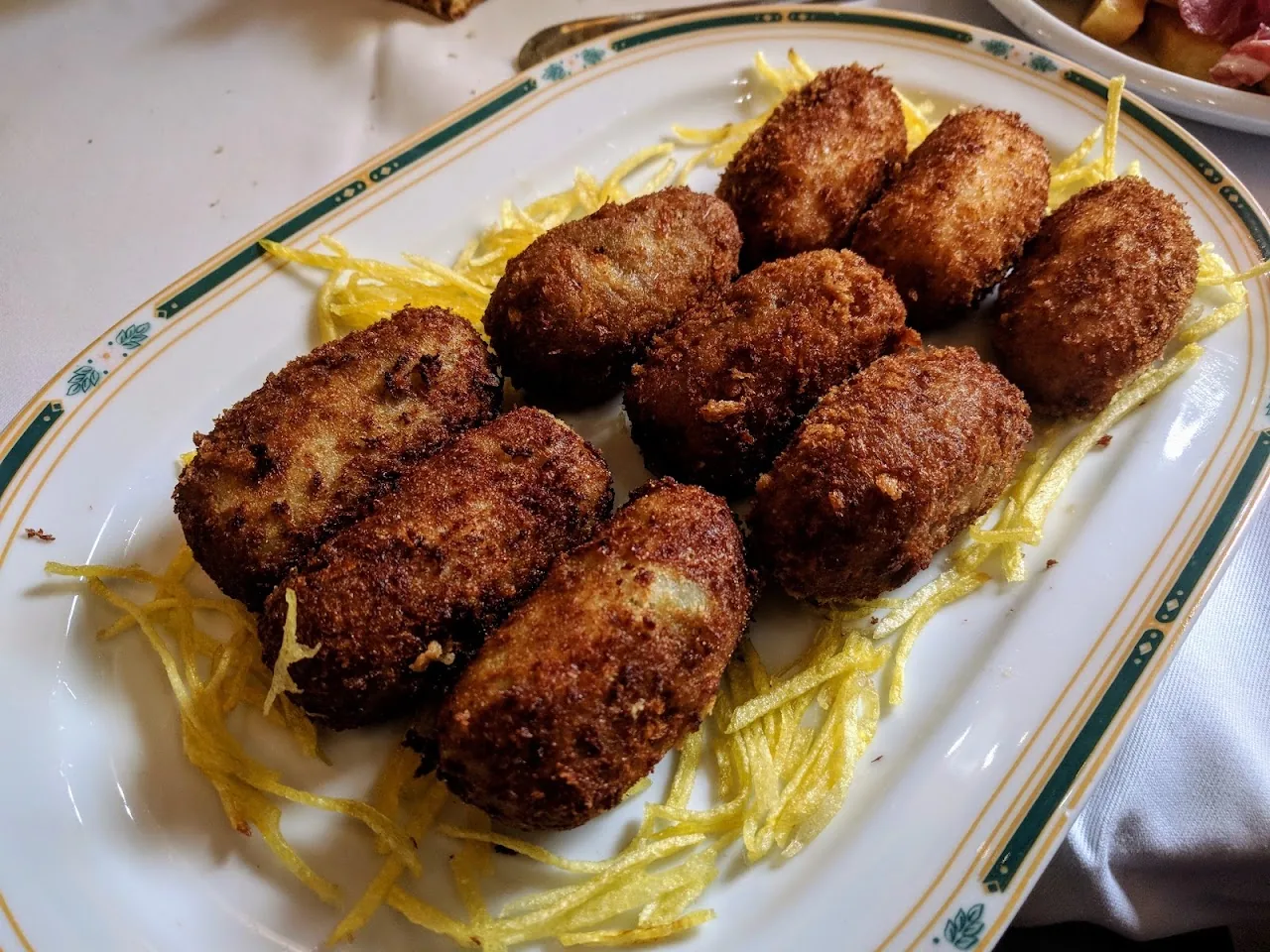 A plate of six breaded croquettes on shredded cabbage