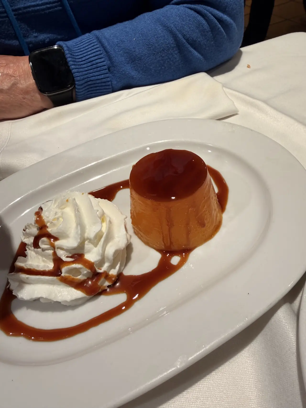 Crème caramel flan topped with whipped cream and caramel sauce