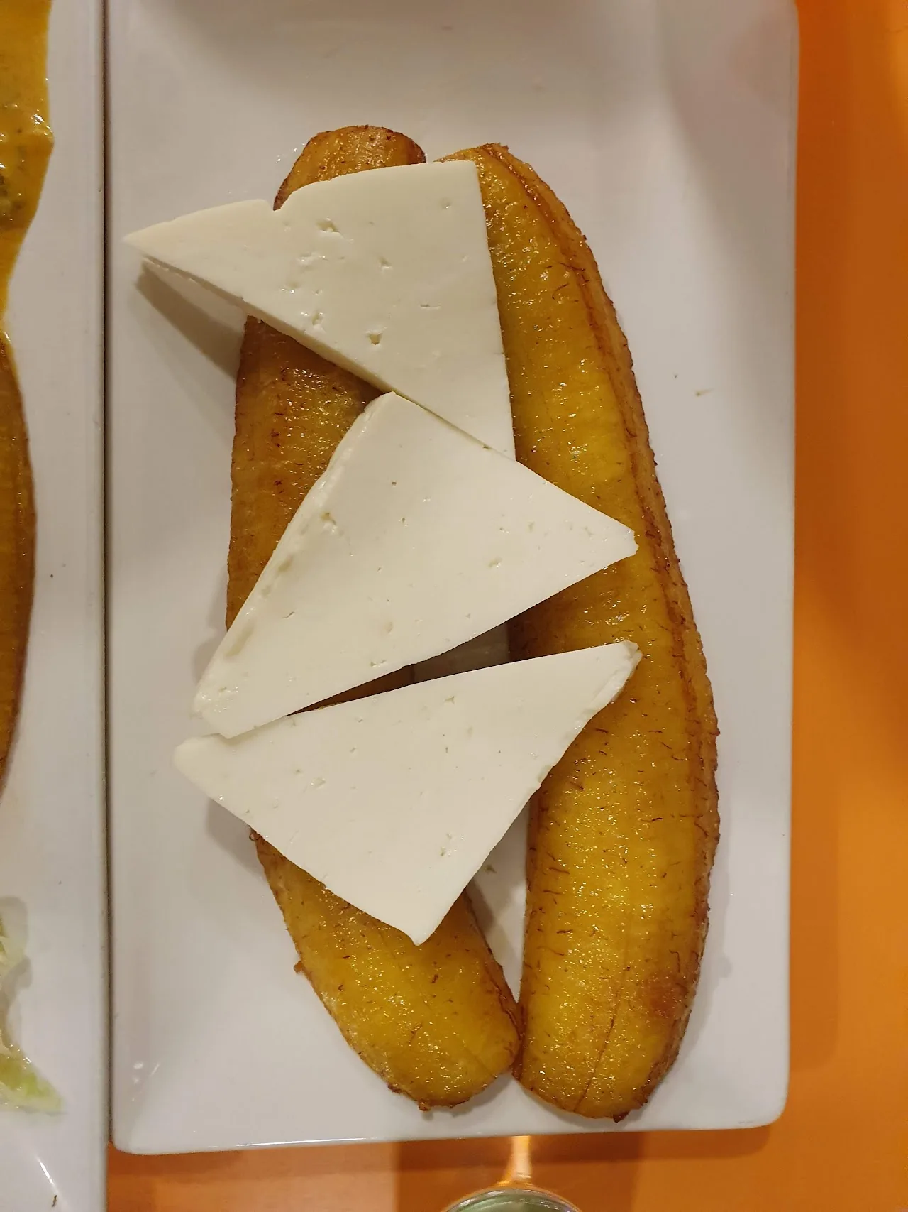 Fried green plantain wedges with slices of white cheese