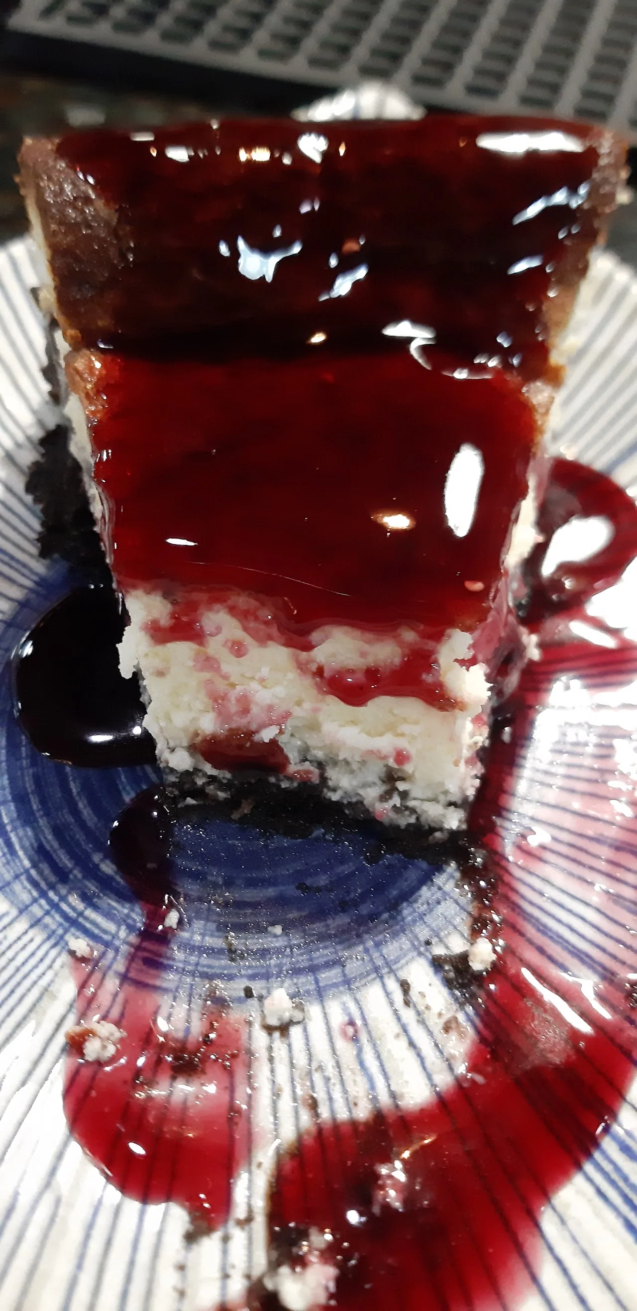 A slice of cheesecake topped with berry sauce