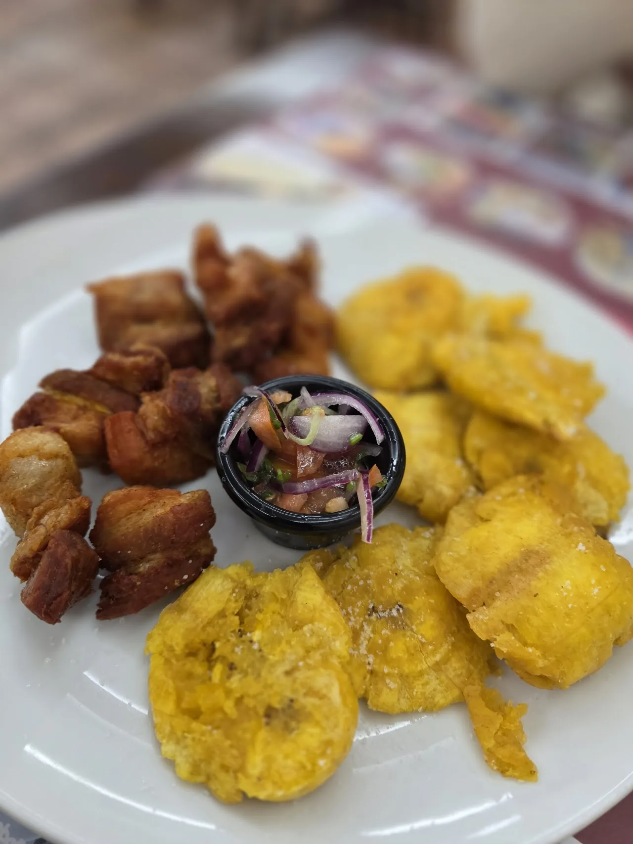 Fried pork chunks served with fried plantains and dipping sauce