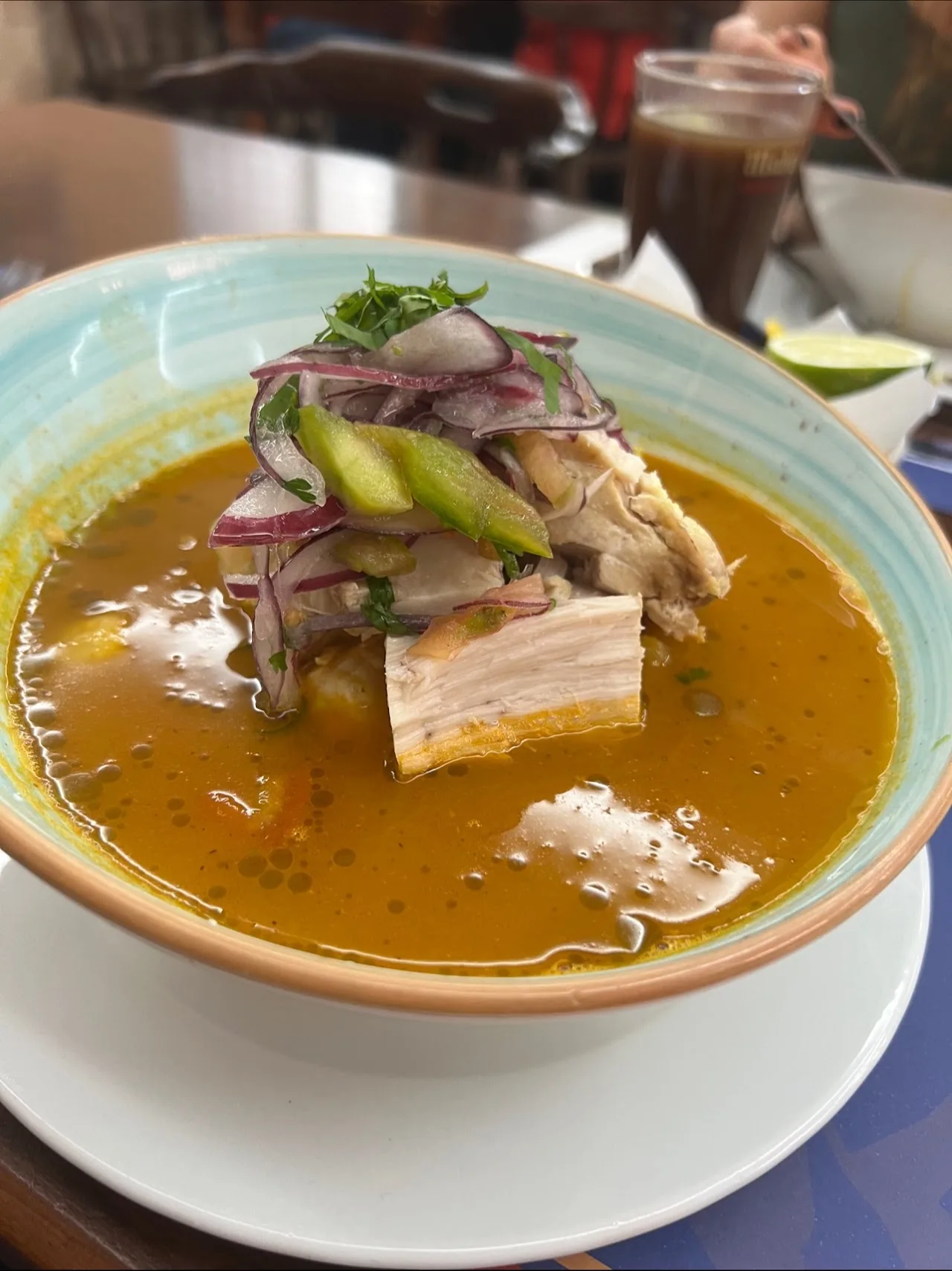 A bowl of seafood soup with rice and a drink