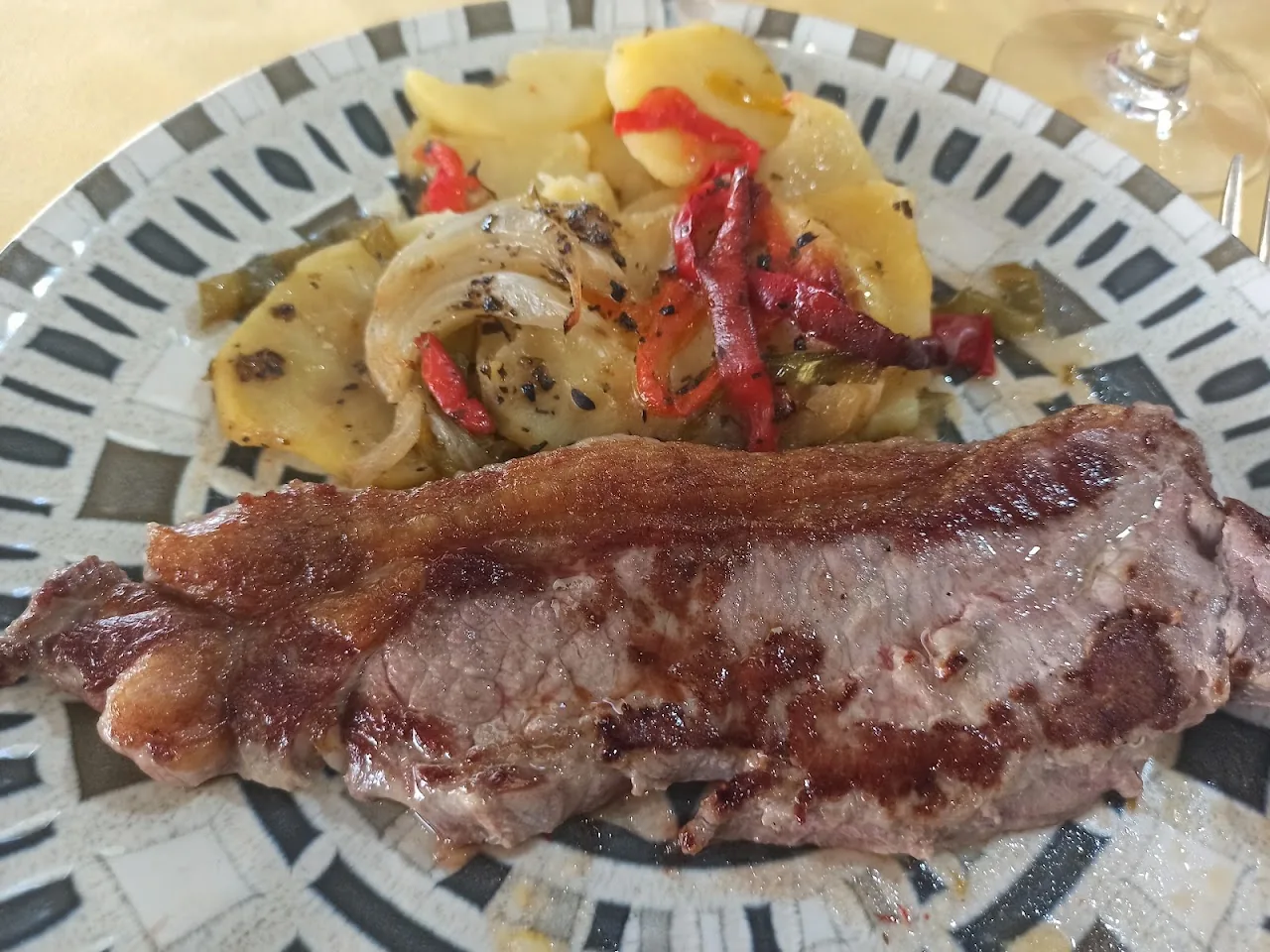 A grilled steak with roasted potatoes and peppers