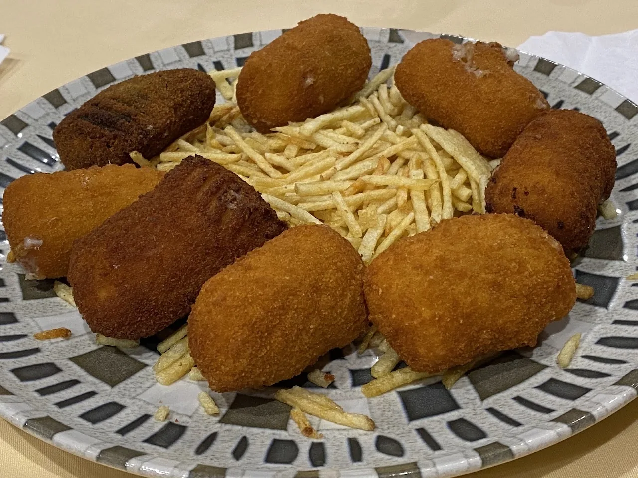 A plate of breaded croquettes with a side of fries