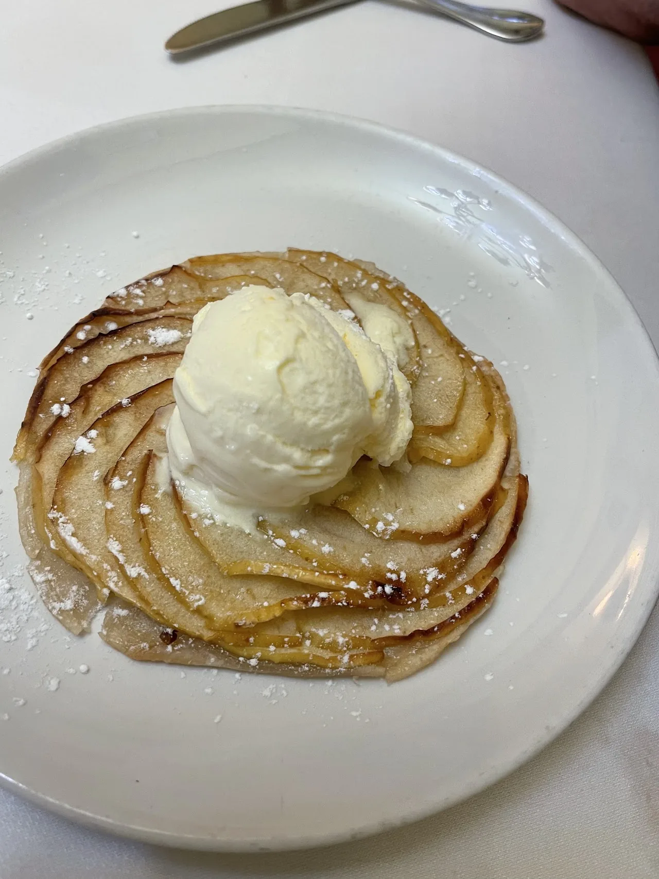 A thin apple tart topped with a scoop of ice cream