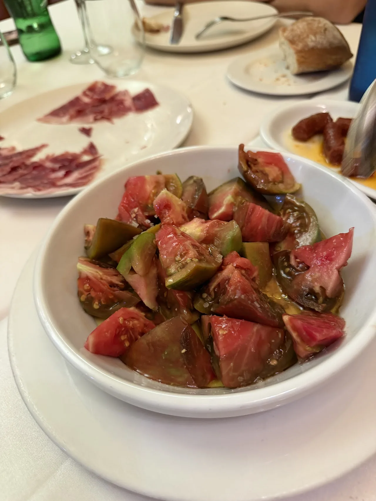 A bowl of gazpacho and a plate of sliced tomatoes with ham