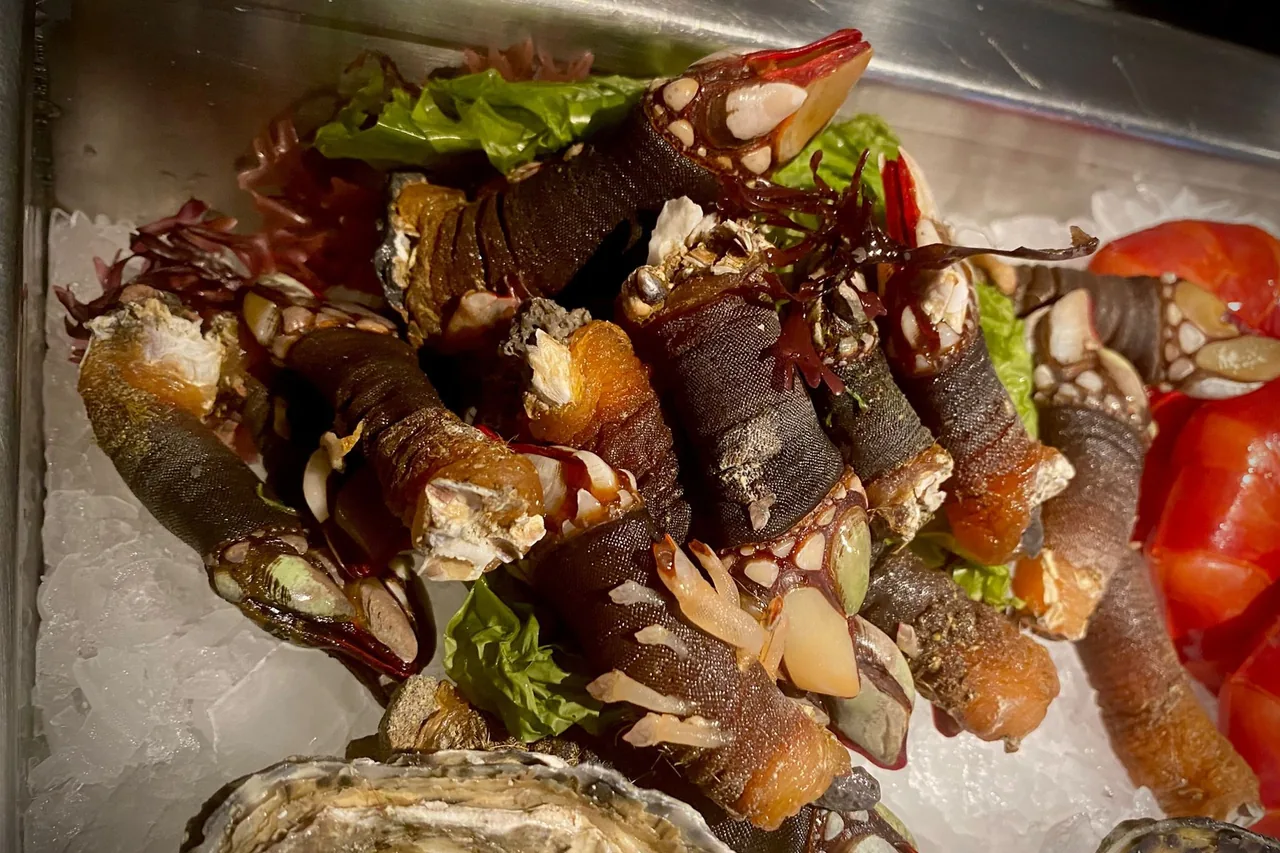 A tray of goose barnacles with tomato and seaweed