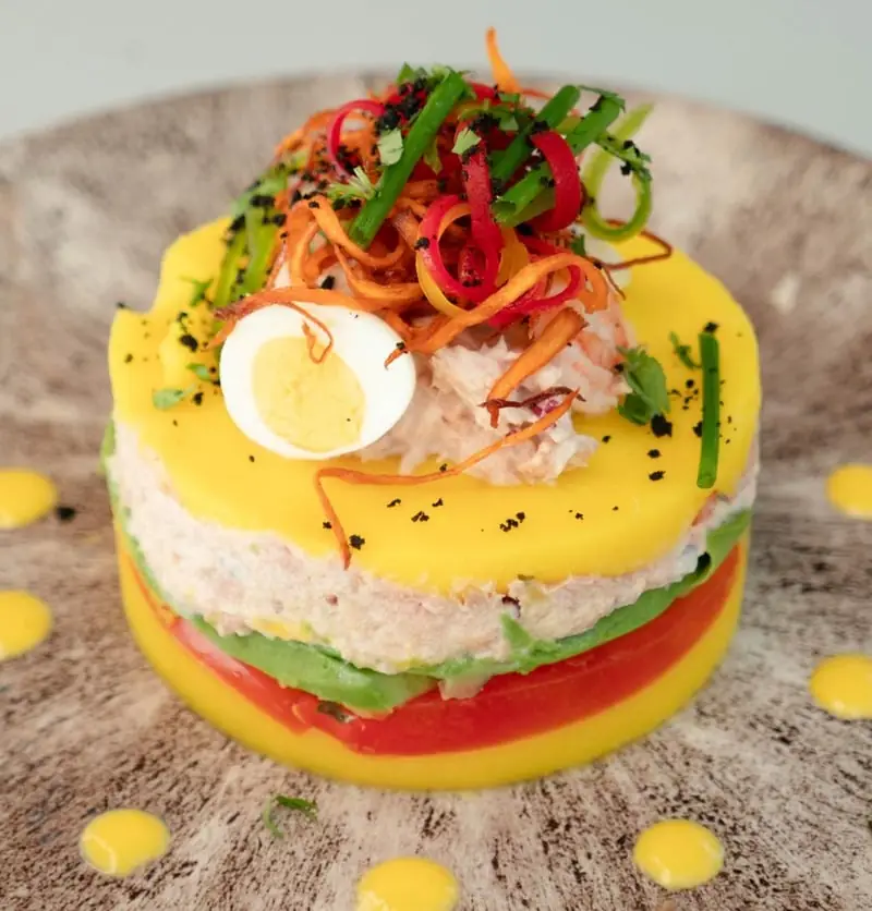 Layered causa limeña topped with shredded seafood, quail egg, and crispy vegetable strands, El Señorío de Perú