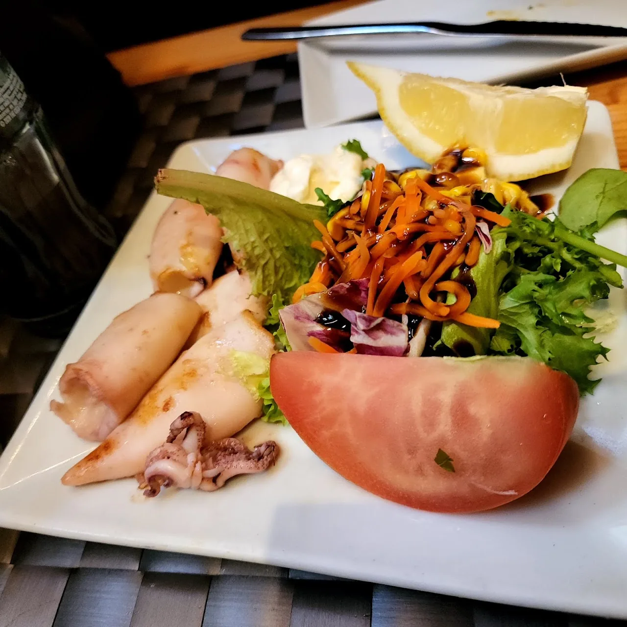 A seafood salad with squid, tomato, and mixed greens