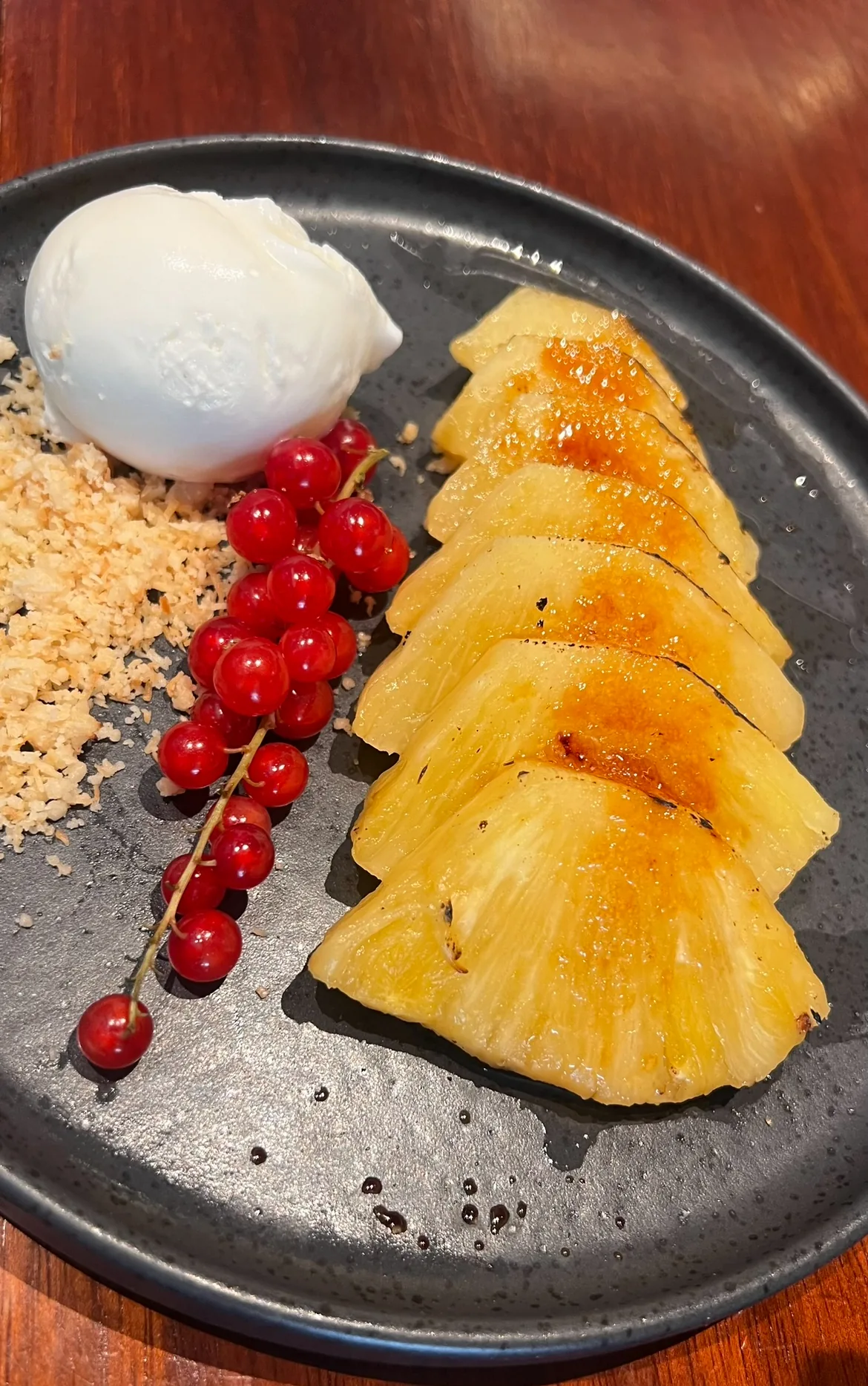 Grilled pineapple slices with ice cream and pomegranate seeds