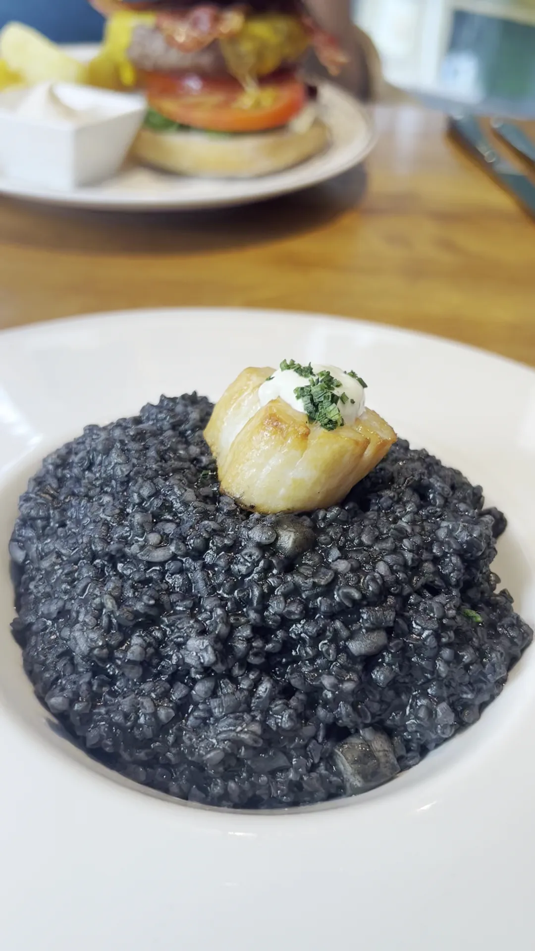 A black rice dish with a burger and dip on the side