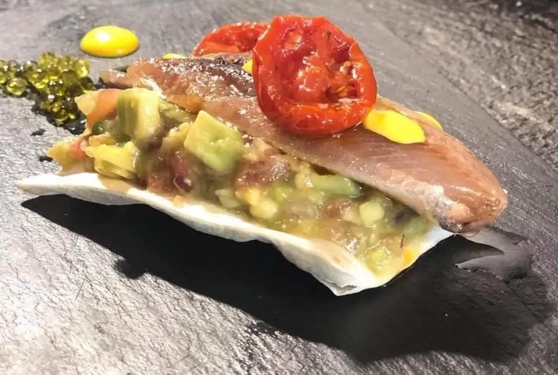 Smoked sardine fillet on avocado tartare over a crisp coca, with roasted tomato