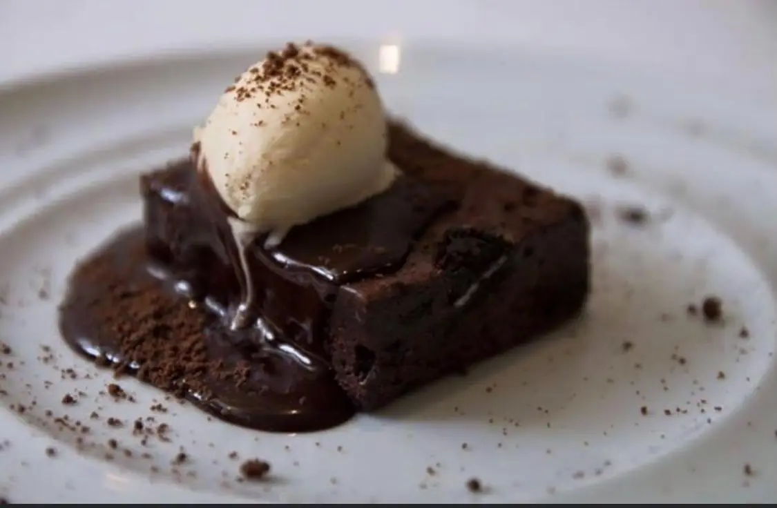 Chocolate brownie with a scoop of ice cream, chocolate sauce and cocoa powder