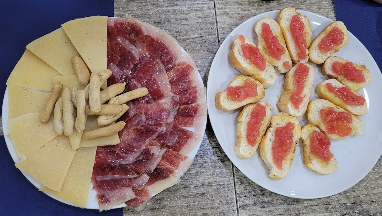 A plate of jamón and cheese sticks next to tomato toasts