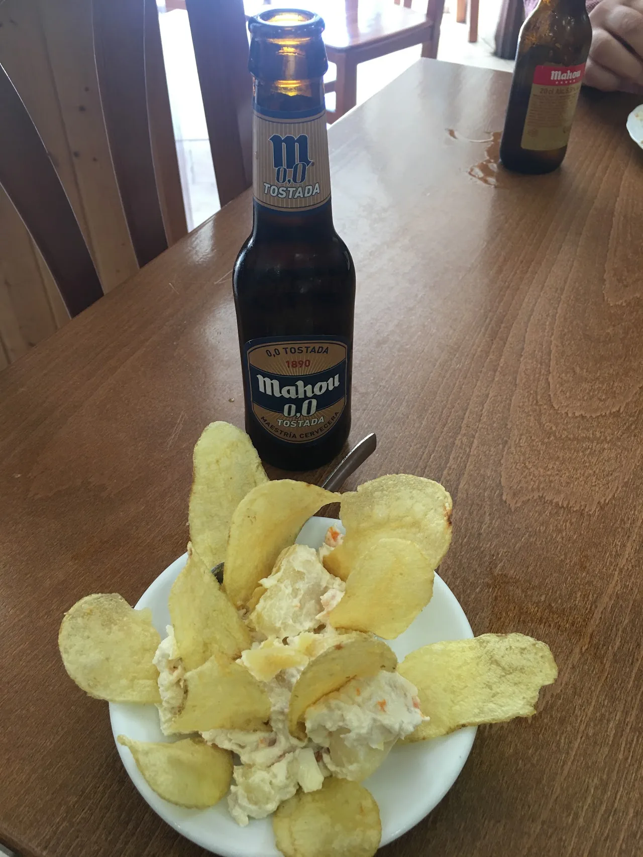 A bottle of beer with a plate of potato chips