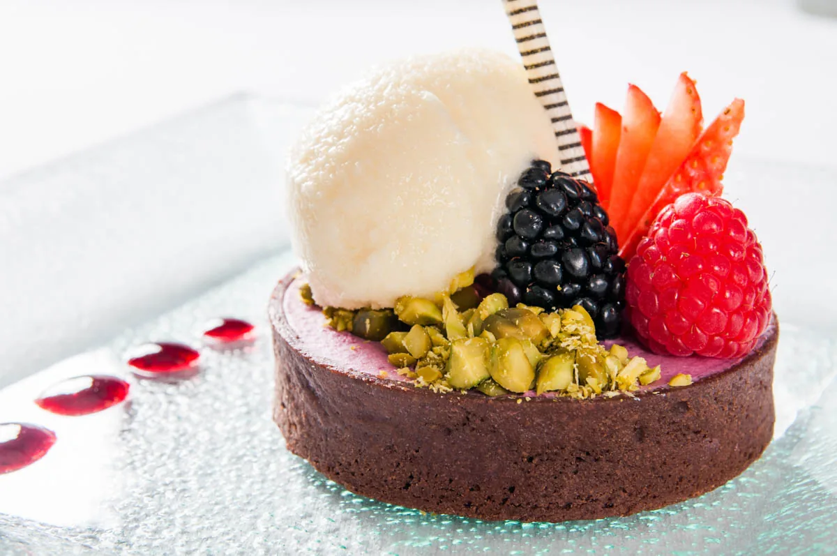 A chocolate dessert tart topped with berries and ice cream