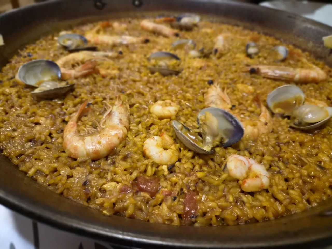 A close-up of seafood paella with shrimp, clams, and chorizo