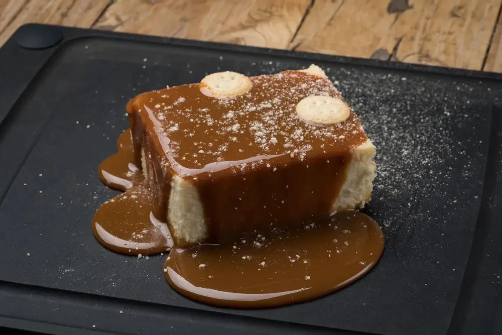 A slice of flan or tres leches cake with caramel sauce