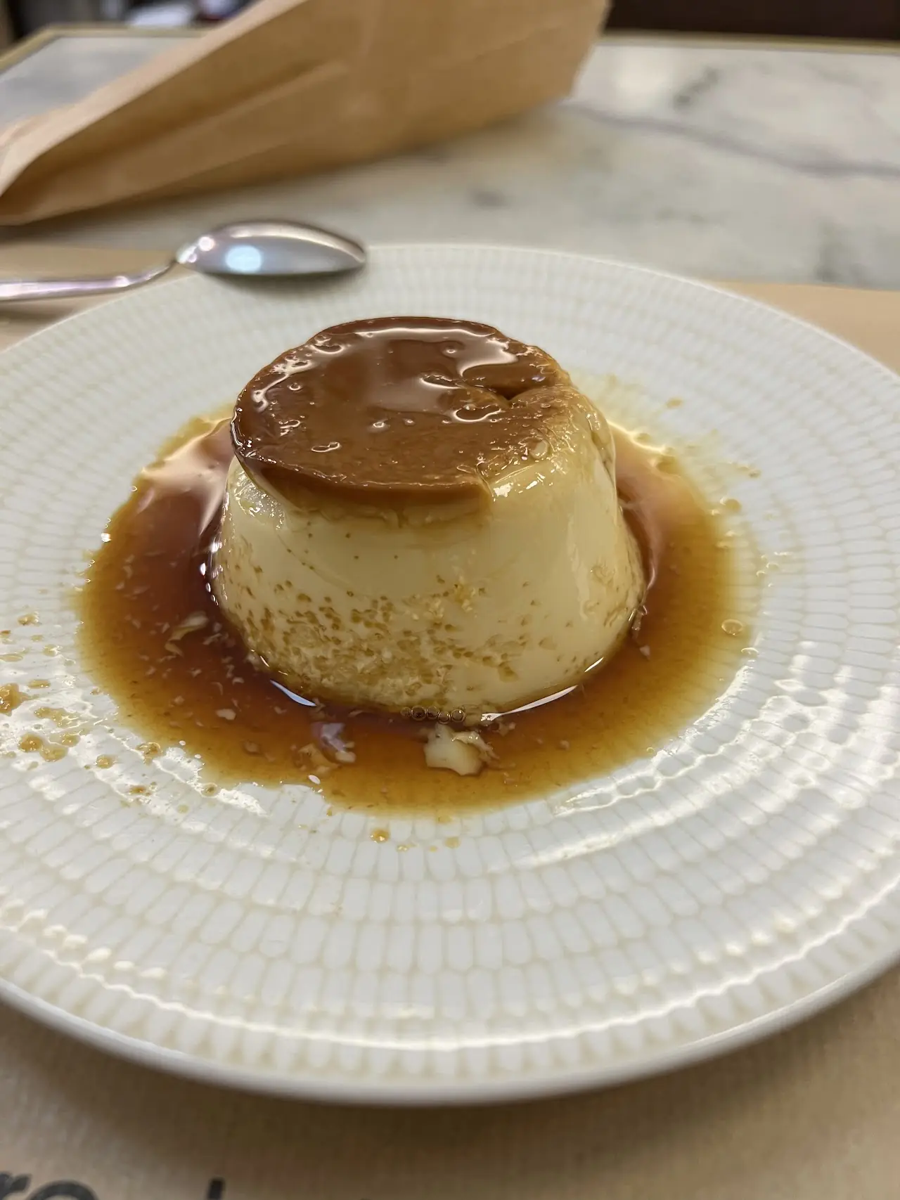 Crème caramel flan in caramel sauce on a white plate, at Elisabets.