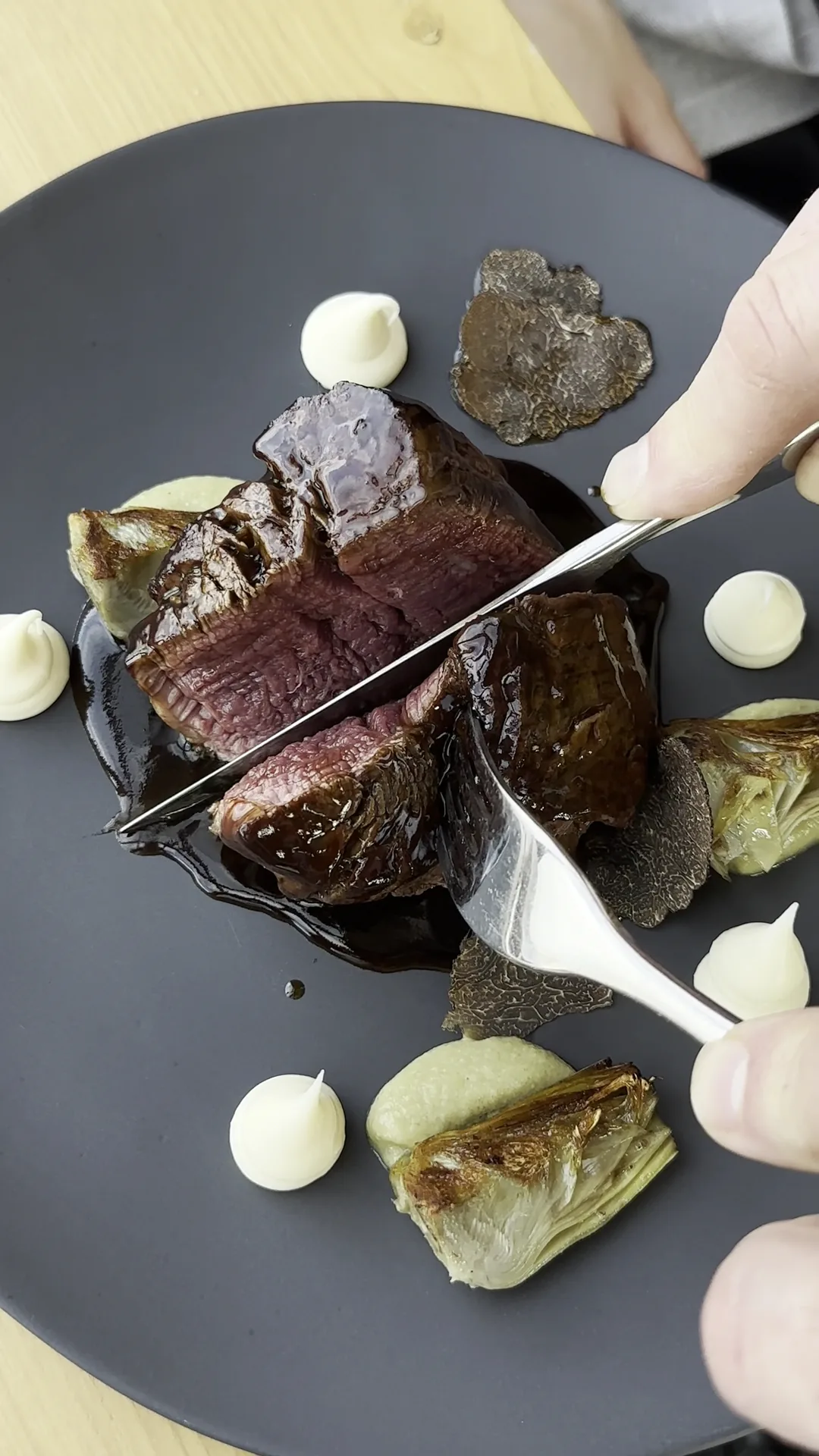 A knife slicing into a wellington-style beef dish with vegetables