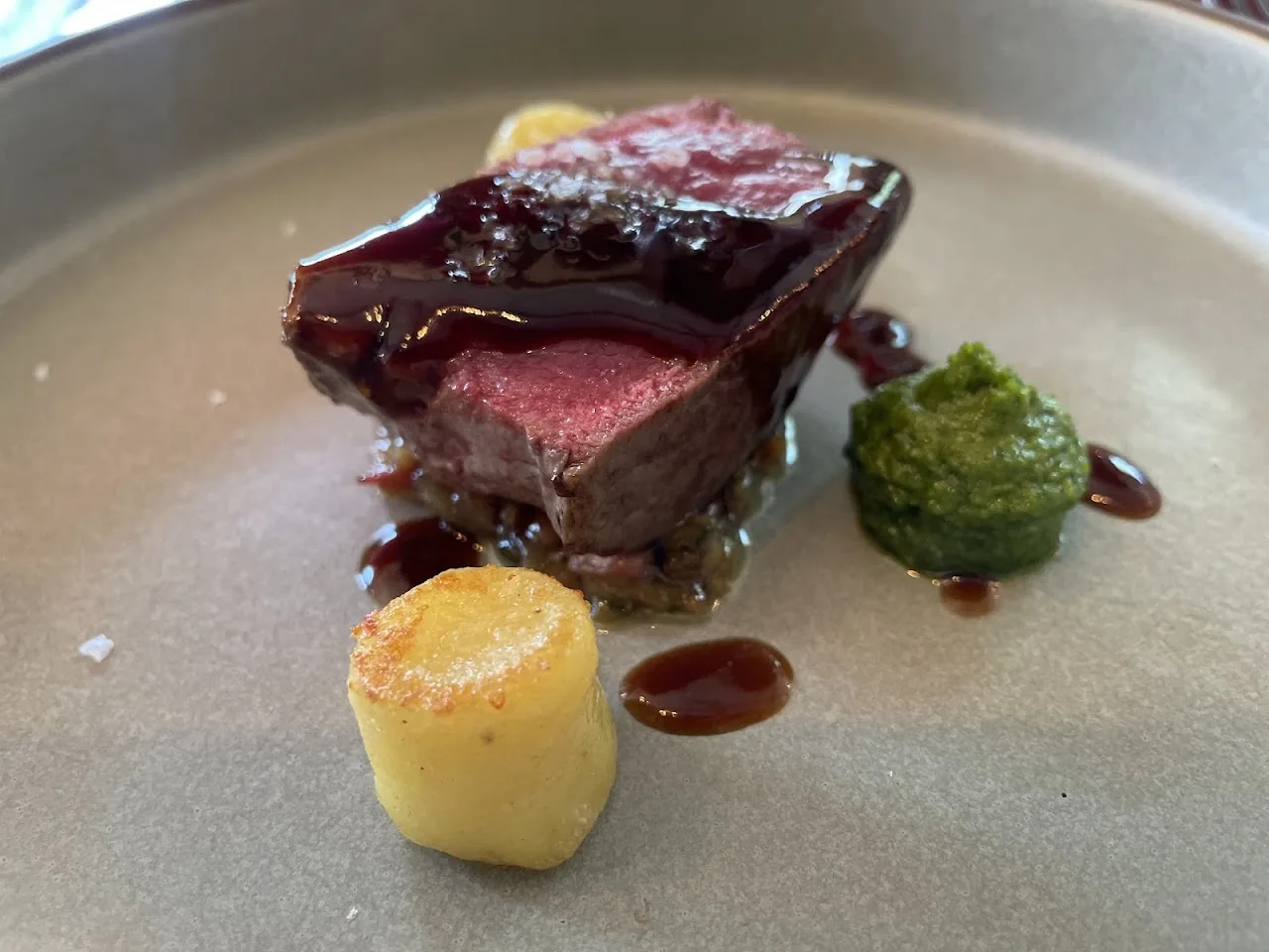 A seared meat dish with a potato purée and dark sauce