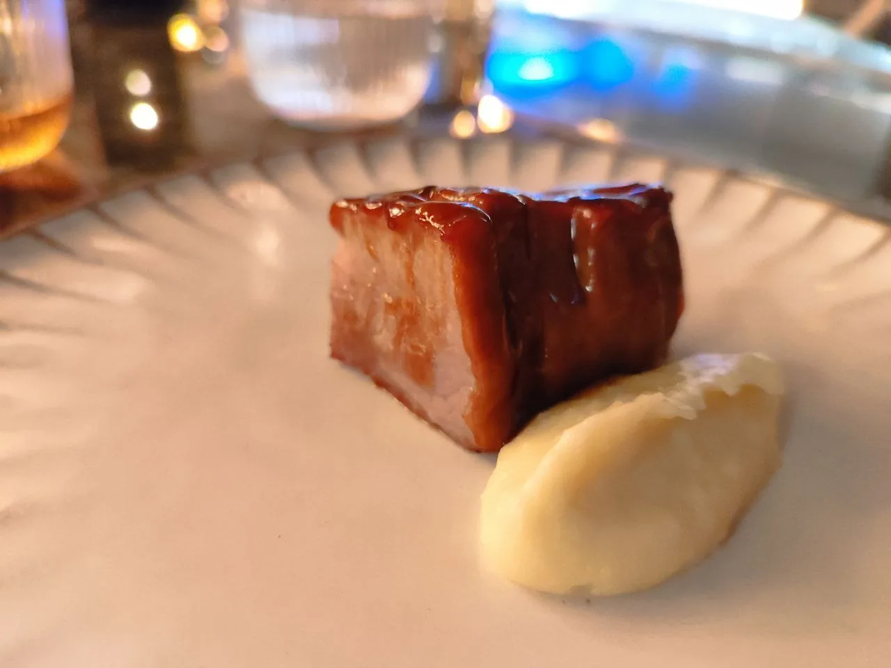 A glazed piece of pork belly with a purée