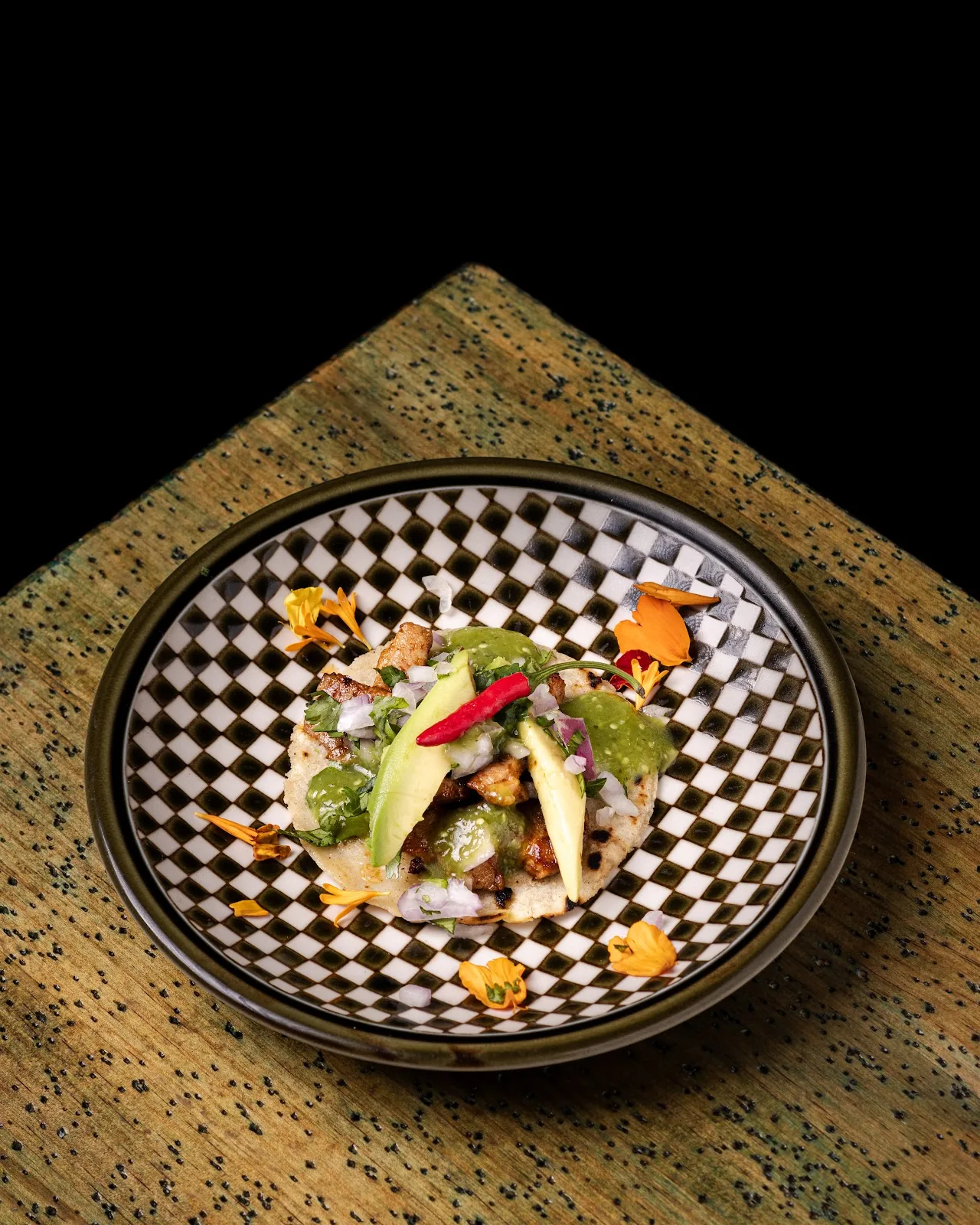An elegant plated dish with citrus segments on a checkered plate