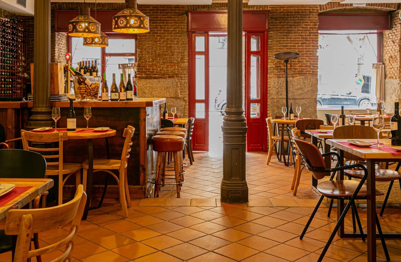 A tavern dining room with a wooden bar, stools and tiled floor