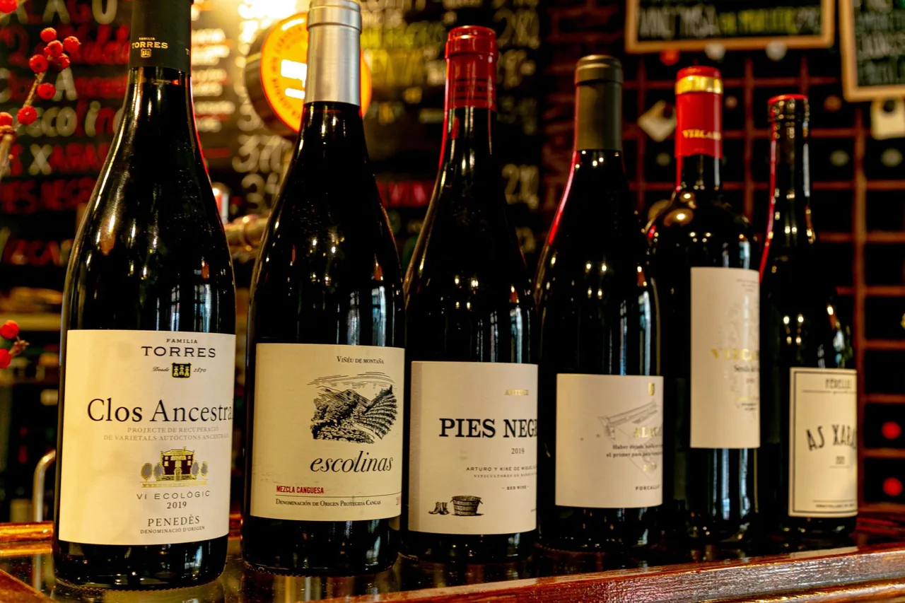 A row of wine bottles standing on a counter in front of wine racks