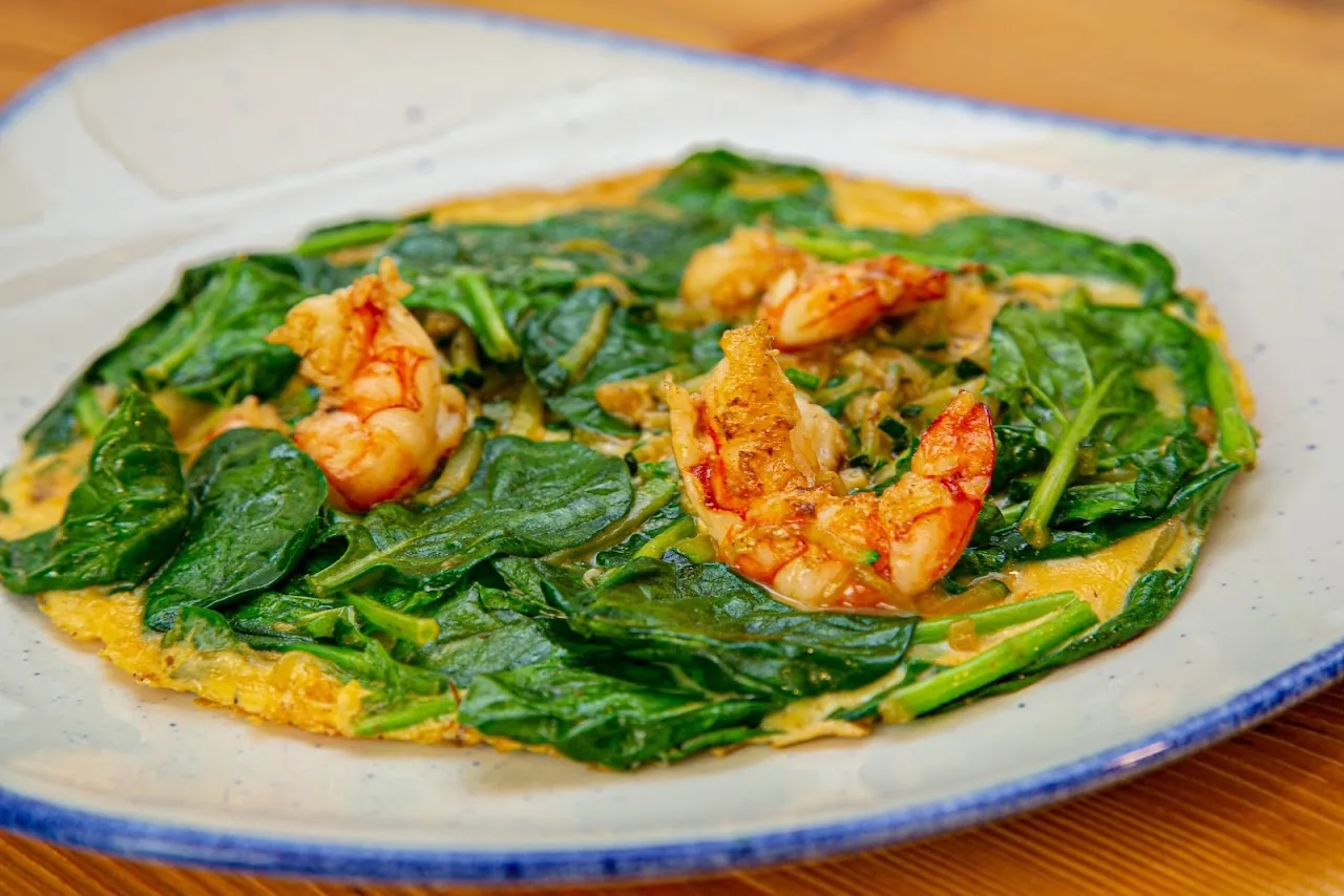 Sautéed spinach with grilled shrimp on a blue-rimmed plate