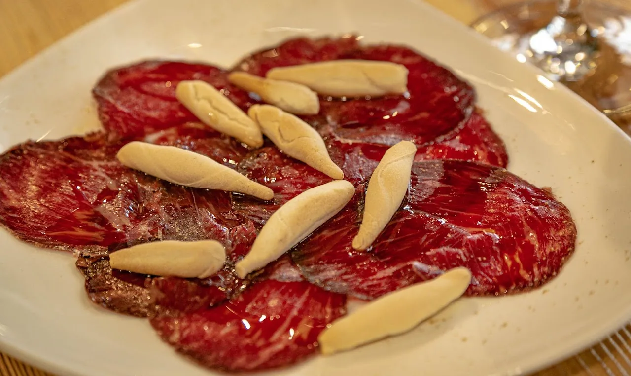 Thinly sliced beef carpaccio topped with shaved cheese