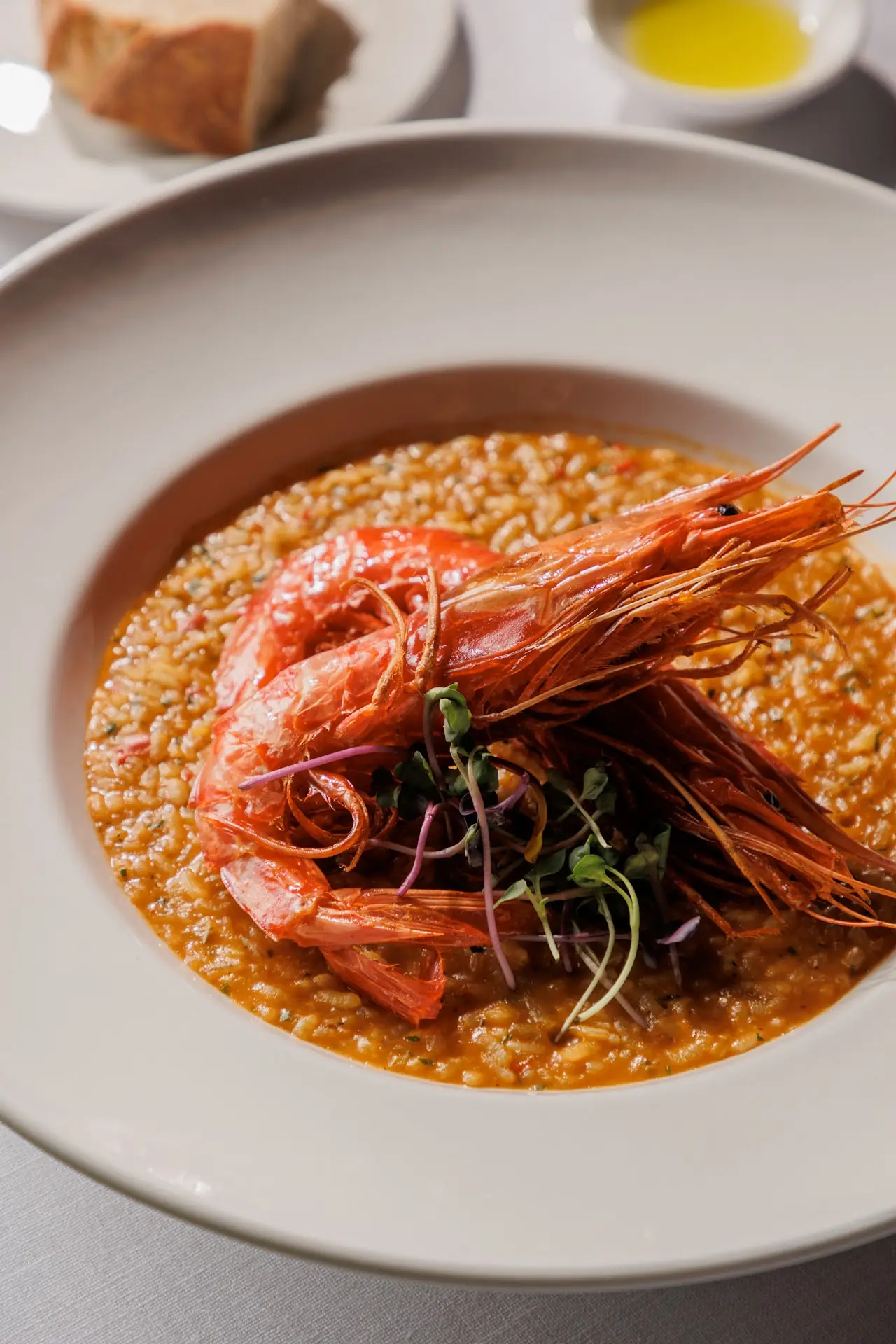 A whole red prawn over saffron rice in a white bowl