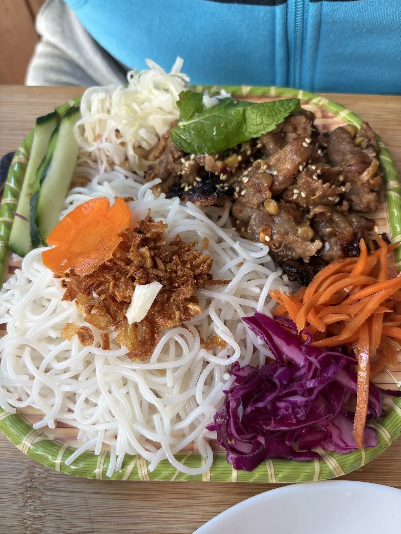 Rice vermicelli with grilled meat, herbs, carrot and red cabbage on a plate