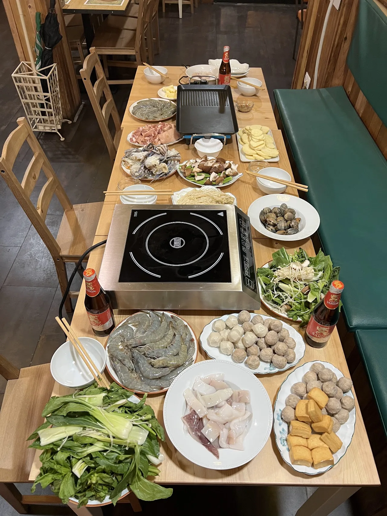 An overhead view of a hot pot spread with vegetables and dipping dishes