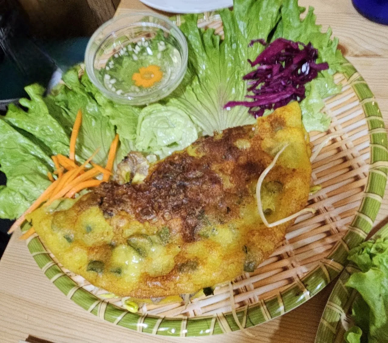 A folded Vietnamese rice-flour pancake (banh xeo) with herbs