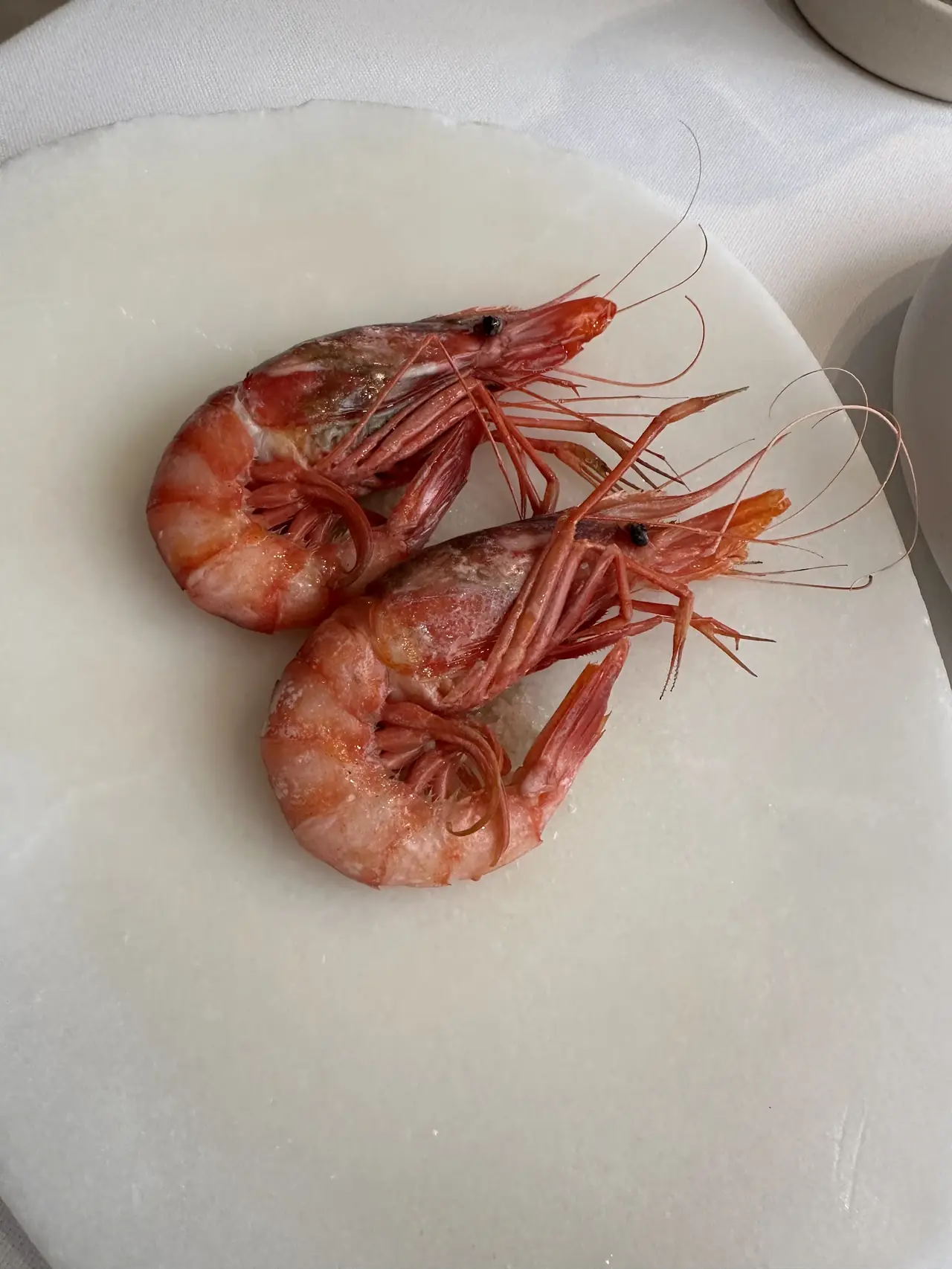 Two whole red prawns served on a white marble plate