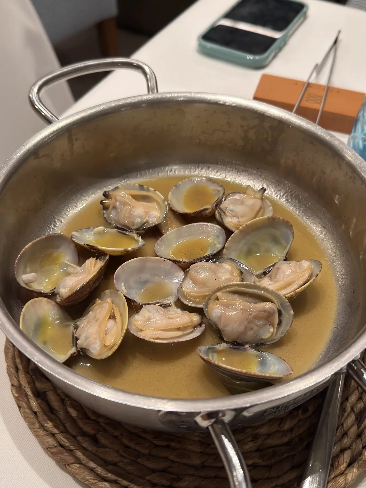 Open clams in broth served in a metal pan
