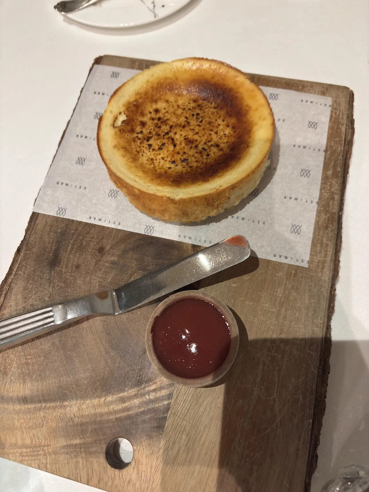 Burnt Basque cheesecake on a board with a small ramekin of red sauce