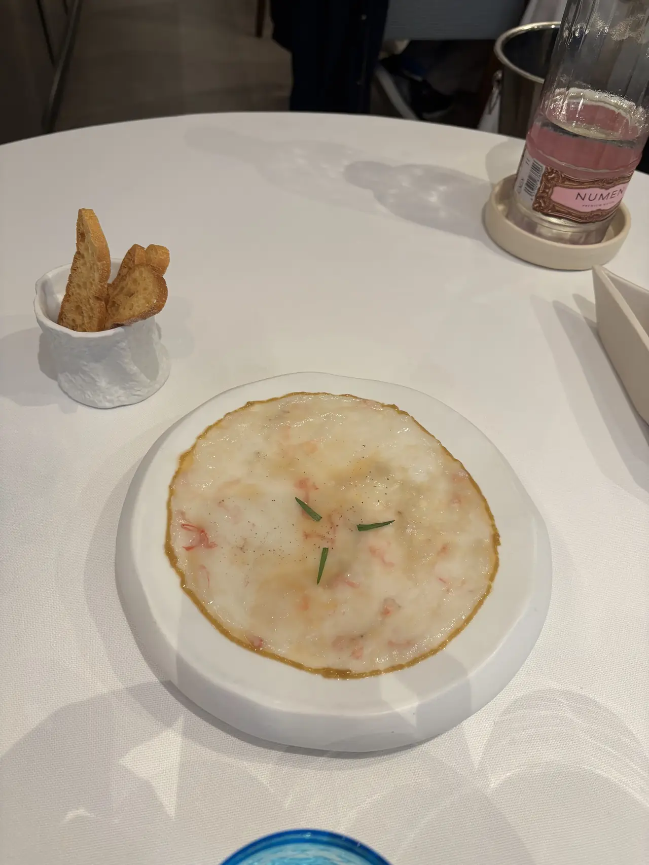Round seafood terrine dish with herb garnish, served with toasted bread on the side