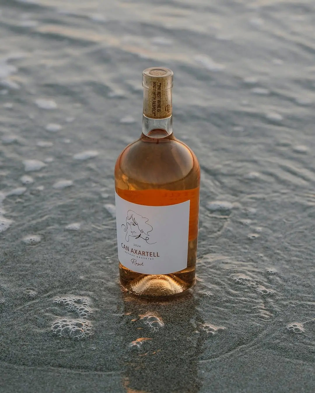A bottle of Can Axartell rosé standing in the sea